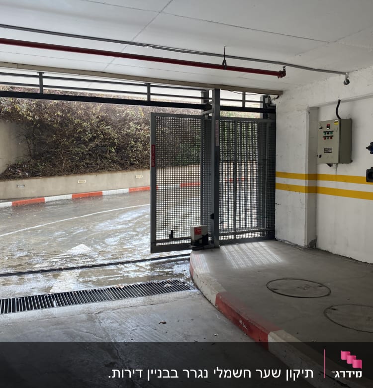 שער חשמלי פתוח בחניון תת קרקעי עם שלט בקרה